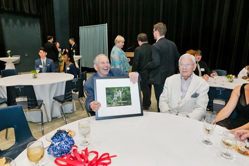 Ewing (center) smiles as he holds a framed picture of dancers as Nick Bragg (center right) looks on.