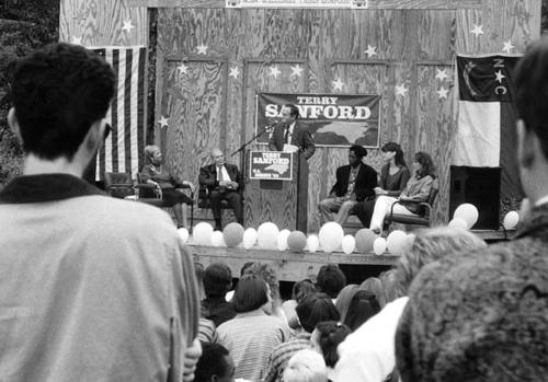 Sanford visiting during his run for Senate. Chancellor Alex Ewing speaking at podium, with Martha Wood (Mayor of Winston-Salem) and Sanford sitting to his right.
