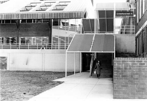 Exterior front-view, with Semans Library on left and Gray Building on right (student walking in middle of image)